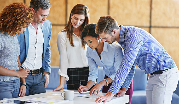 Young, diverse team in business casual dress discussing documents