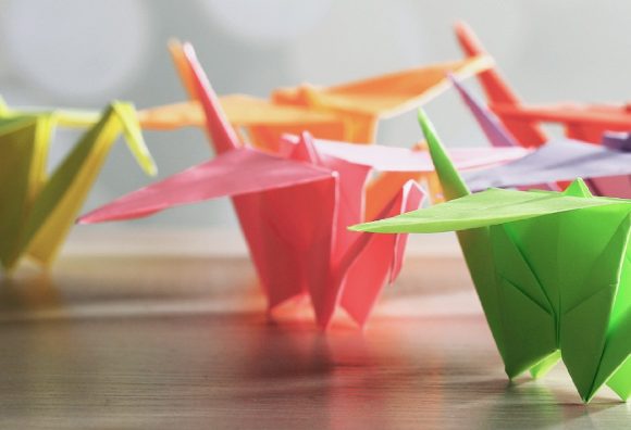 Diverse colorful paper swans in group on table looking forward